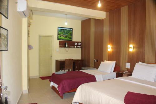 a hotel room with two beds and a desk at Welcome Inn in Ella
