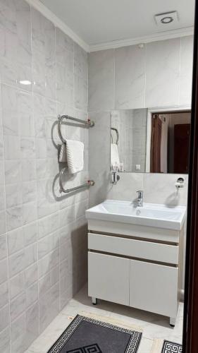 a white bathroom with a sink and a mirror at Белес in Astana
