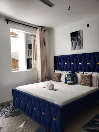 a large bed with a blue headboard in a bedroom at SPACIOUS VIP 1 BEDROOM with ROOFTOP SWIMMING POOL AVAILABLE in Mtwapa