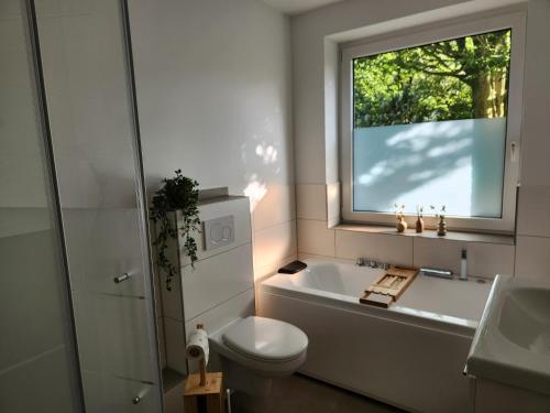 a bathroom with a tub and a toilet and a window at Borndal-Zeit in Altenberge