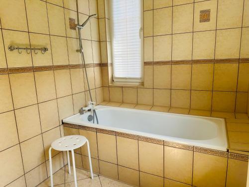a bathroom with a tub and a stool in it at Dom w Niechorzu dla 8 osób z dużym ogrodem - 5D Apartments in Niechorze