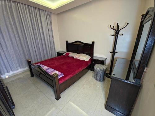 a bedroom with a bed with a red comforter at Ayla Shalet Villa in Al Kufayr