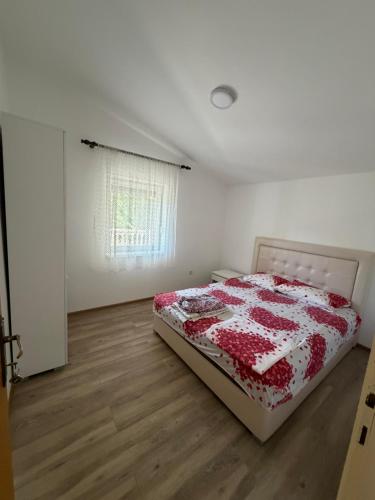 a bedroom with a bed with a red and white quilt at Apartman Sambi 3 in Čanj
