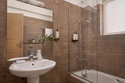 a bathroom with a sink and a glass shower at Sandy Beach Resort by Rizos Resorts in Agios Georgios