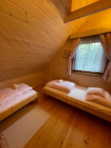 two beds in a wooden room with a window at Soliński Zając in Werlas
