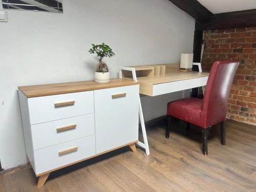 a desk with a red chair next to a white cabinet at Rembrandt Hostel in Krakow