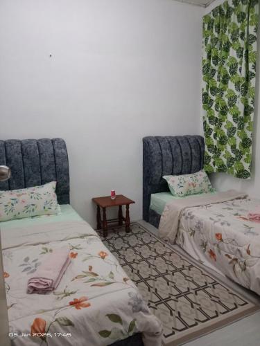 a room with two beds and a table in it at Homestay Casa Mutiara in Paka