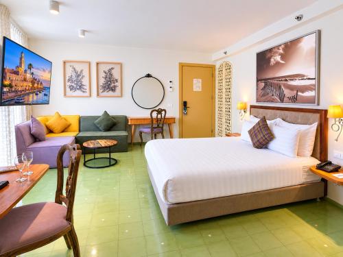 a hotel room with a bed and a couch at Margosa Boutique Hotel Tel-Aviv Jaffa in Tel Aviv