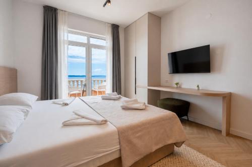 a bedroom with a bed with a desk and a window at Villa Sunce Beachfront in Podgora