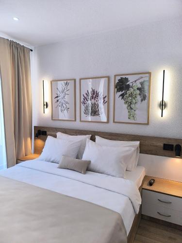 a bedroom with a large white bed with four pictures on the wall at Kostadinov Residence in Demir Kapija