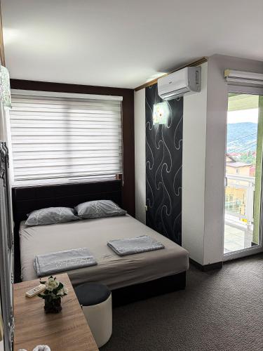 a bedroom with a bed and a table and a window at Harmony Rooms & Apartments in Vogošća