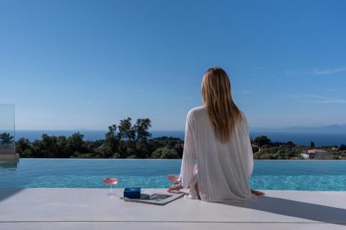 a woman sitting on the edge of a pool at CAPO LEFKADA Villa 97 - Sea View - Two Private Pools in Tsoukalades