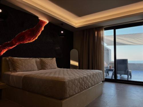 a bedroom with a bed and a large window at Bevimar Suites with Private Pool and Non Heated Jacuzzi in Santorini