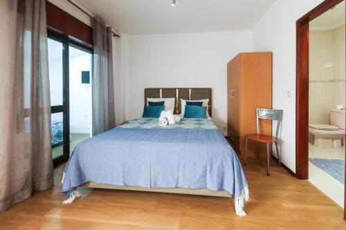 a bedroom with a bed with blue sheets and a toilet at Apartamentos e quartos Primorosa in Nazaré