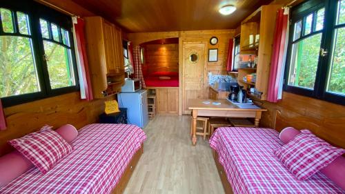 two beds in a small room with a kitchen at La Dorépontaise ROULOTTE in Pondaurat