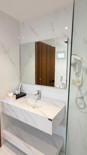 a white bathroom with a sink and a mirror at سراة للشقق الفندقية in Al Namas