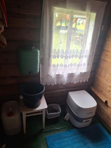 a small bathroom with a toilet and a window at Šimtametis namelis in Anykščiai