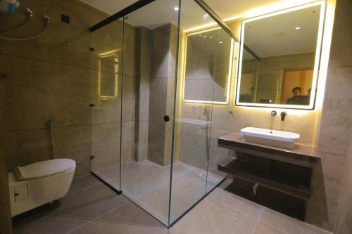 a bathroom with a shower and a toilet and a sink at Chunmun Elite Retreat in Bulandshahr