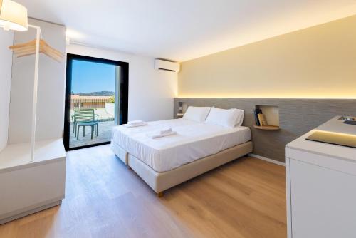 a white bedroom with a bed and a balcony at Appart'hotel Saint Francois in Calvi