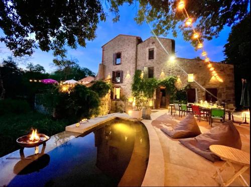a house with a pool in front of a building at Le moulin du Guy, proche du Puy duFou in La Ménie