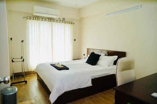 a bedroom with a large white bed and a window at Hola Properties in Dhaka