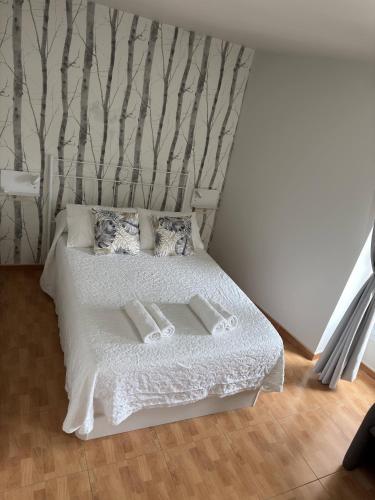 a bedroom with a white bed with trees on the wall at Apartamento Linde in Muros