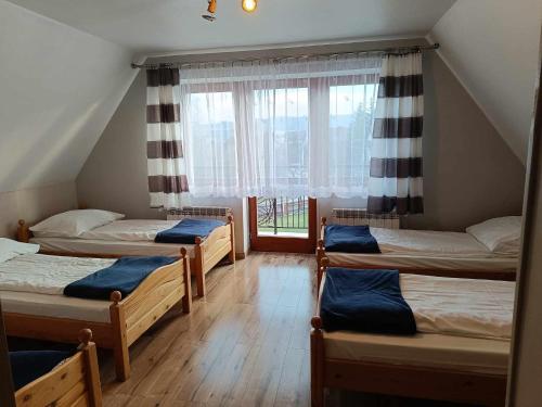 a group of four beds in a room with a window at Dom Wczasowy Kazik in Maniowy