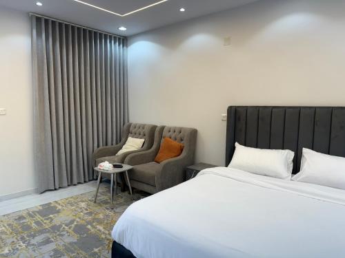 a hotel room with a bed and two chairs at شقق النخبة The Elite department in As Sayl aş Şaghīr