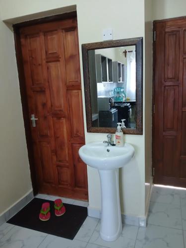 a bathroom with a sink and a mirror and two slippers at Mbeyustays in Malindi