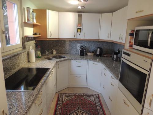 a kitchen with white cabinets and a microwave at Sonniges Paradies mit Seeblick und Panoramaterrasse in Lugano