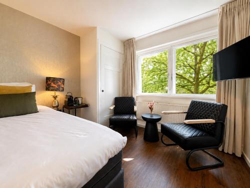 a bedroom with a bed and two chairs and a window at Paping Hotel & Spa - Rest Vonck by Flow in Ommen