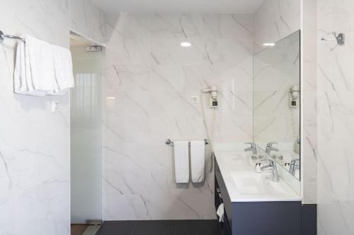 a white bathroom with a sink and a shower at Hotel Fatima Center in Fátima