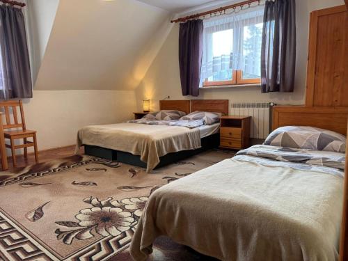 a bedroom with two beds and a rug at Kobakówka in Krynica Zdrój