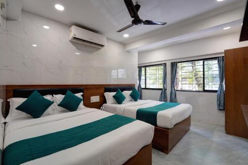a bedroom with two beds with green and white sheets at Hotel Benz Inn in Mumbai