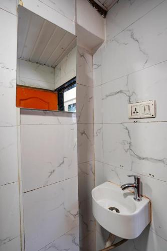 a white bathroom with a sink and a mirror at Hotel Benz Inn in Mumbai