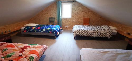 a attic room with two beds and a window at La ferme du lac Saint Front in Saint-Front