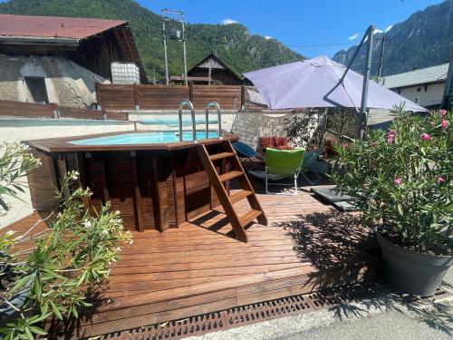 a wooden deck with a hot tub and an umbrella at Mazot en Abondance in Vacheresse