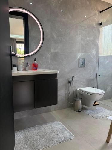 a bathroom with a sink and a toilet and a mirror at Villa with pool, ping pong table, trampoline in Mellah Bakka