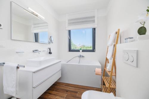a white bathroom with a tub and a sink at Villa LeSt in Gabonjin