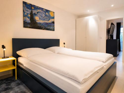 a large white bed in a bedroom with a painting on the wall at Luxury Apartment Königsallee Old Town Rhine Promenade Messe in Düsseldorf