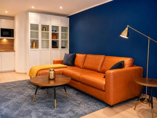 an orange couch in a living room with a blue wall at Luxury Apartment Königsallee Old Town Rhine Promenade Messe in Düsseldorf