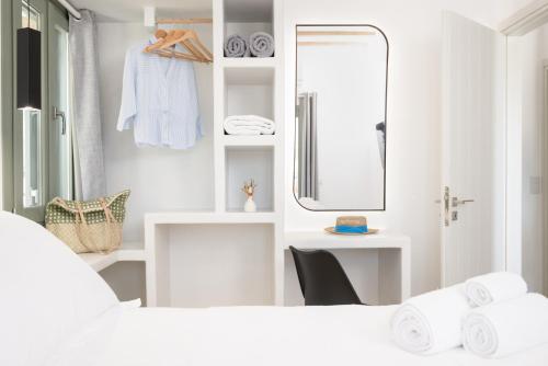 a white bathroom with a mirror and a bed at À La Plage Residences 03 in Platis Gialos