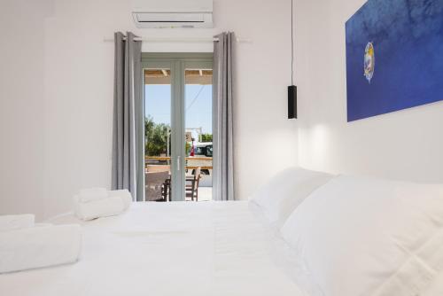 a bedroom with a white bed and a sliding glass door at À La Plage Residences 03 in Platis Gialos