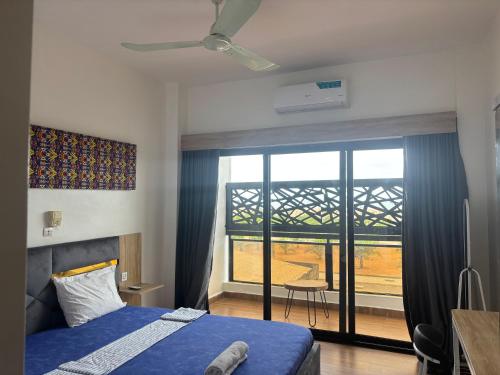 a bedroom with a blue bed and a large window at Chez Gero Aeroport in Cotonou