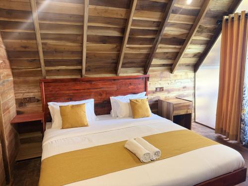 a bedroom with a large bed with two towels on it at Glenora Wood Cabin in Ella