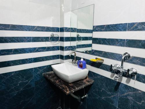 a bathroom with a white sink and blue and white stripes at The Aura Grand Hotel and Cafe in Patna