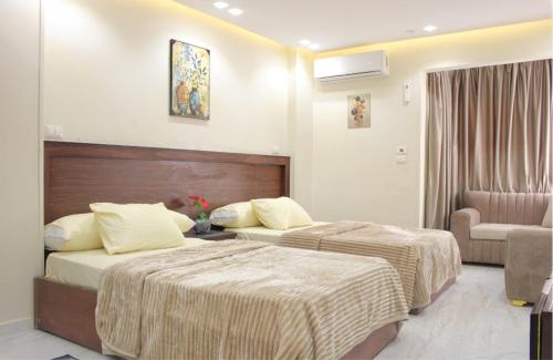 a hotel room with two beds and a chair at Hana Grand Hotel in Madinat Al Ashir min Ramadan