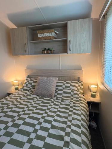 a bedroom with a bed with a black and white checkered bedspread at Dotties Den at Sunnysands in Llanddwywe