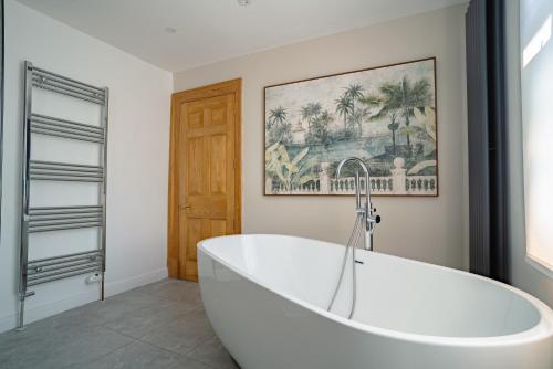 a white tub in a bathroom with a picture on the wall at St James House Timeless Comfort Central Congleton in Congleton