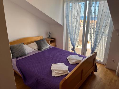 a bedroom with a purple bed and a large window at Guest House Lav in Primošten